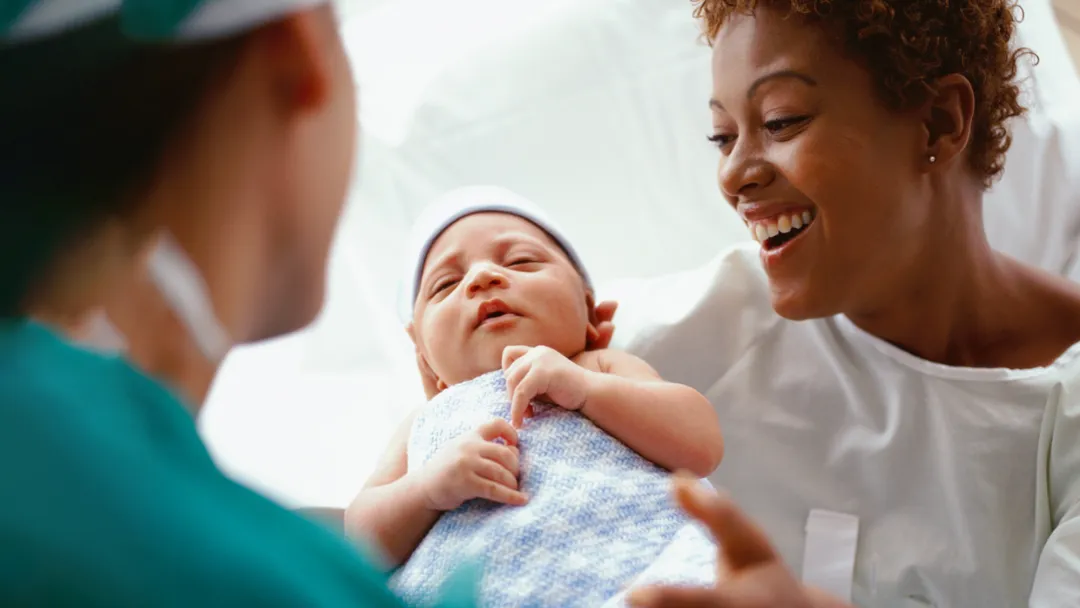 A new mother being handed her newborn baby.
