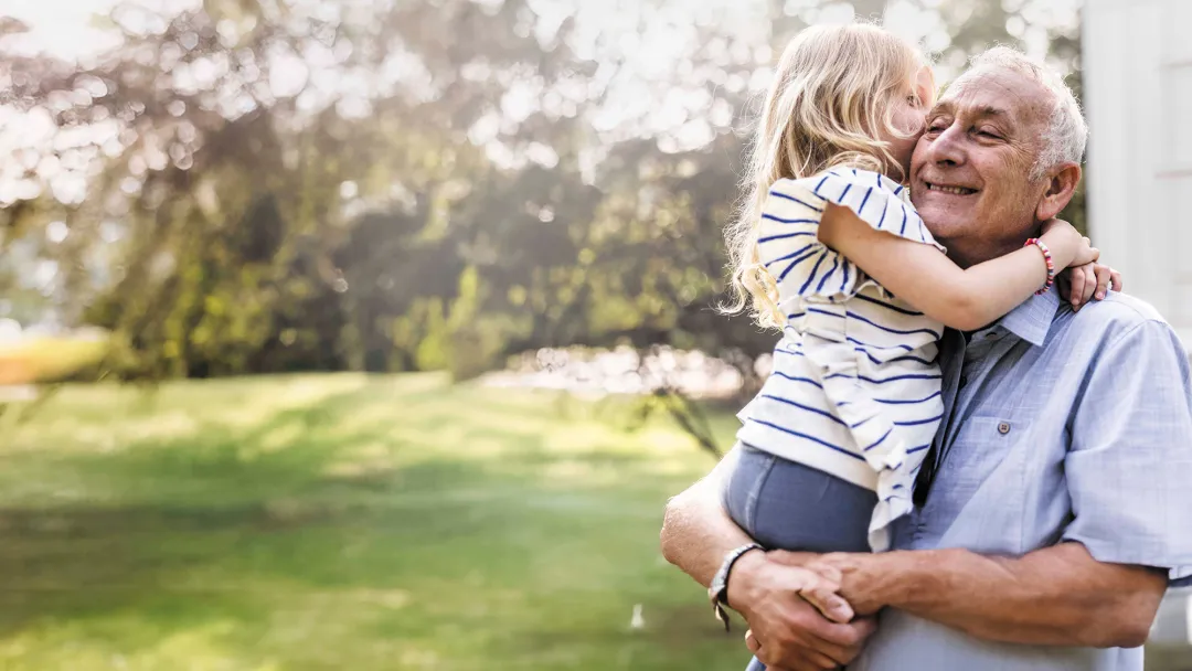 Senior Man Smiling, Holding Granddaughter.