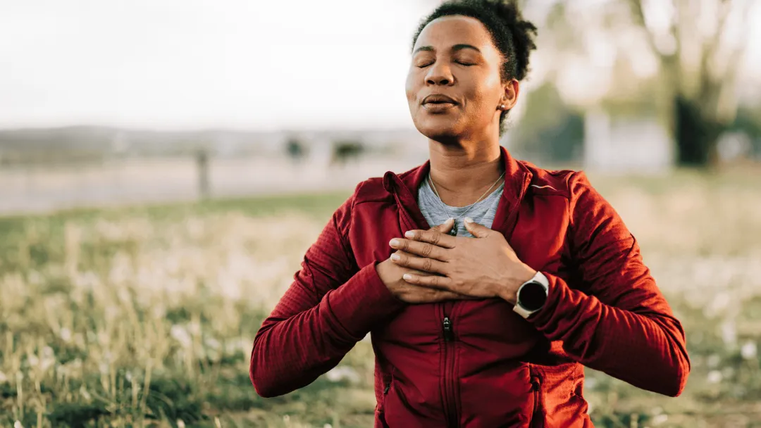Woman taking a deep breath outdoors.