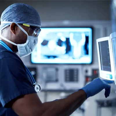 A Doctor Examines a Patient's Information on a Monitor During a Procedure