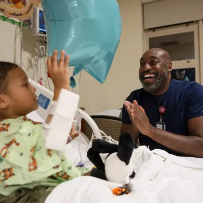 Man Nurse With Child Holding Balloon in Emergency Room Smiling 