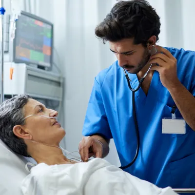 Doctor listening to senior patient's heart in ER