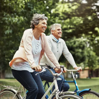 Older couple riding bikes outdoors together,