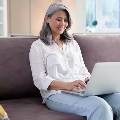 A woman using her computer while sitting on the couch.