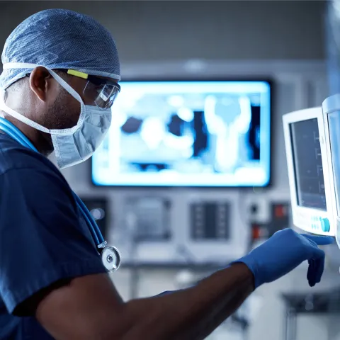 A Doctor Examines a Patient's Information on a Monitor During a Procedure