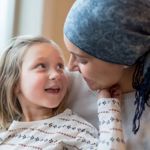 A Small Child Smiles and Touches Her Mother's Face While Sitting in a Window.