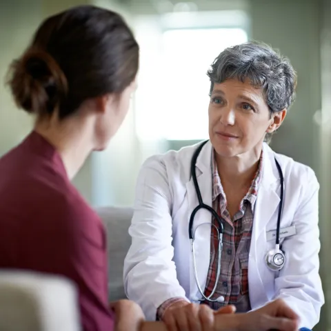 A female doctor comforts a young woman in her office