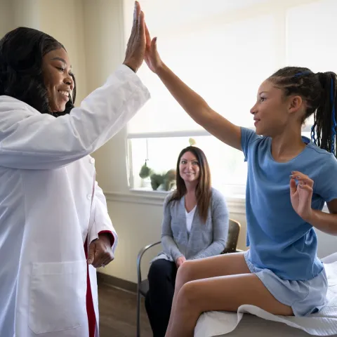 Physican with Child and Mother in Medical Office Room.
