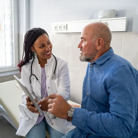 Physician converses with patient holding a tablet.
