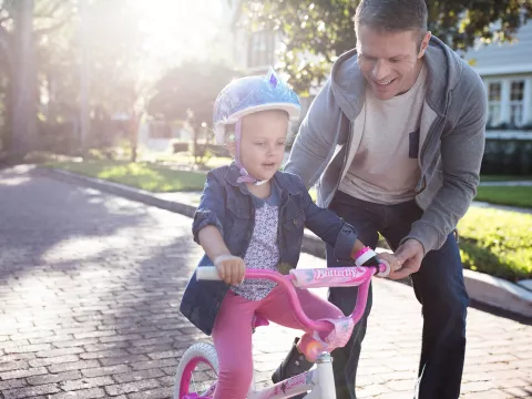 Father teaching daughter to ride a bike in neighborhood.