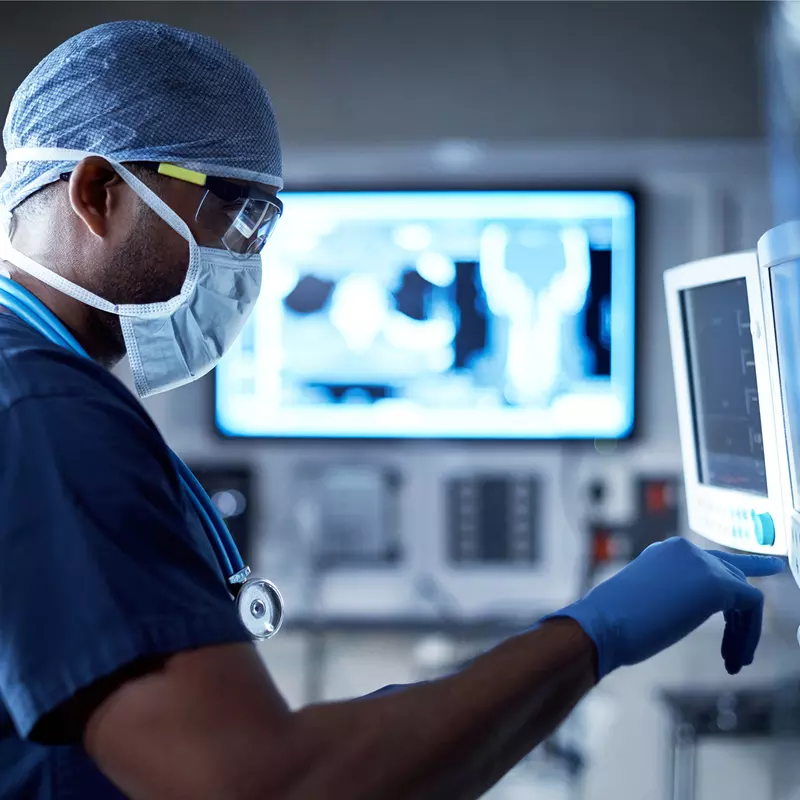 A Doctor Examines a Patient's Information on a Monitor During a Procedure