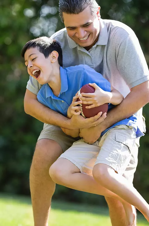 Dad playing football with son outdoors.