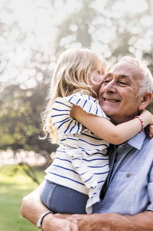 Senior Man Smiling, Holding Granddaughter.